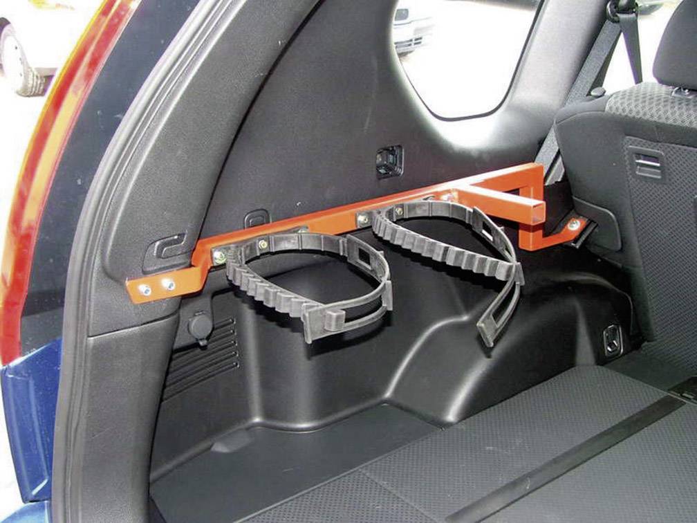 Orange fire extinguisher bracket in the boot of a vehicle, with two black retaining straps.