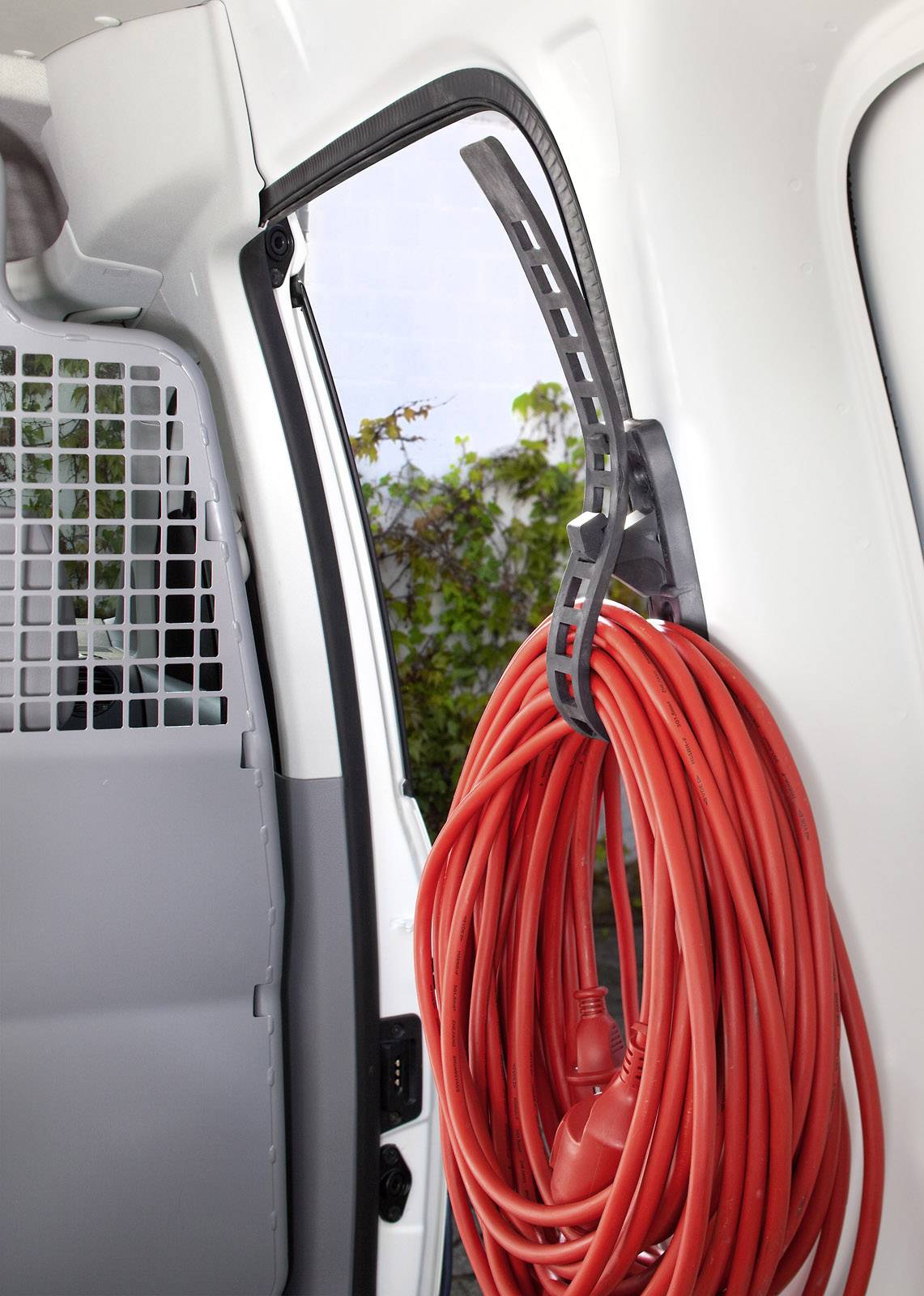 A red extension lead is neatly coiled hanging in a van. Parts of the interior are visible in the background.