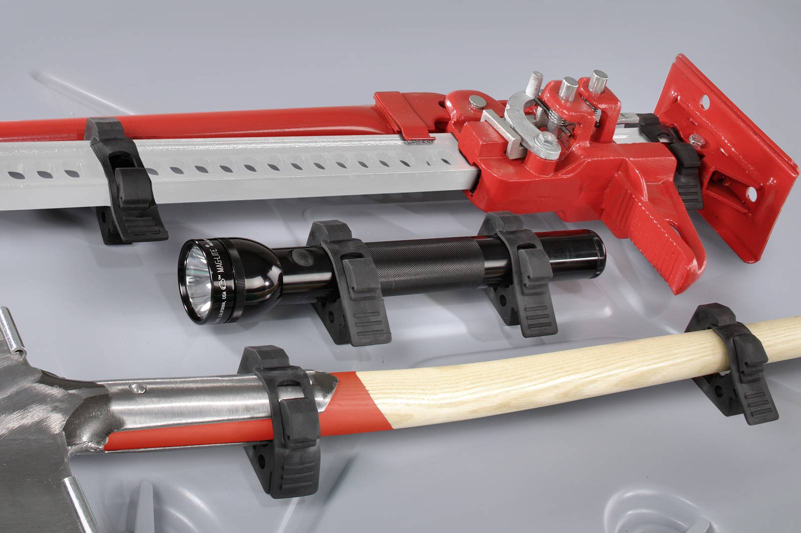 Tool holder with red lever, torch and spade in black clips on grey surface.