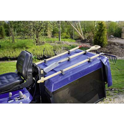 Lawn tractor with attached gardening tools such as a spade, rake, and shovel. In the background, a garden with trees and shrubs.
