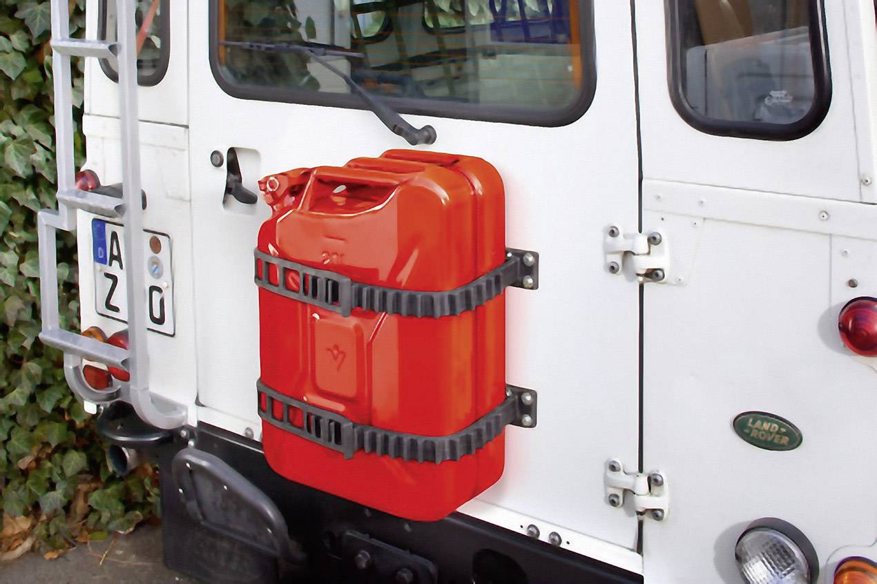 A red petrol can is secured with straps to the rear of a white off-road vehicle.