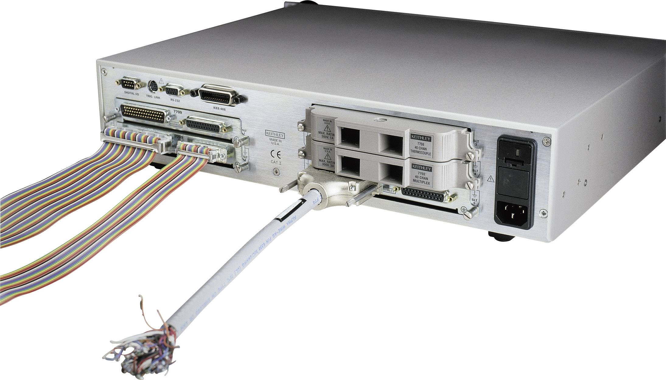 Back of an electronic device with multiple ports and cables. On the left, a multi-core flat ribbon cable runs along the surface.