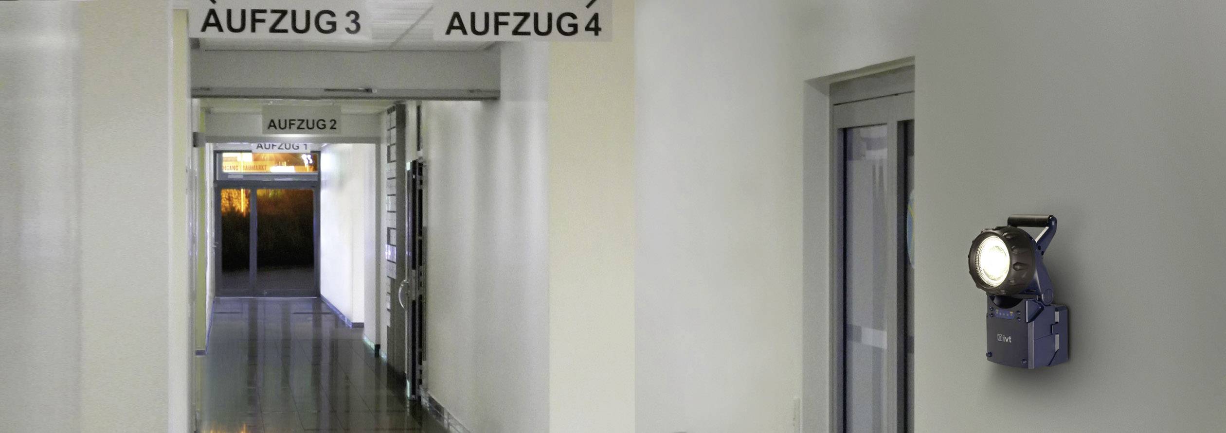 A corridor with doors to lifts, labelled 'Lift 2', 'Lift 3' and 'Lift 4'. To the left, glass doors can be seen leading outside.