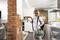 A woman is working on an exposed brick wall with an electric tool. She is wearing a protective mask and safety glasses.