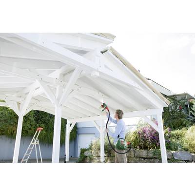 A person is painting the white wooden framework of a carport outdoors using a spray device. A ladder stands nearby.