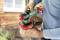A person is holding a green and red spray gun and preparing it for use, likely in a garden or on a terrace.