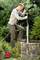 A person is installing a pump in a well, surrounded by dense vegetation. They are using a glove to secure the device.