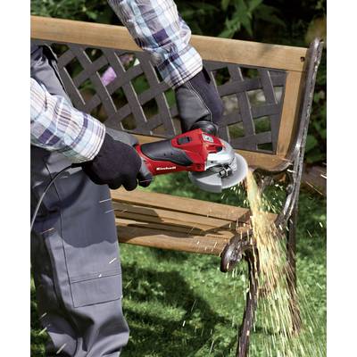 A person is cutting a metal bench with an angle grinder. Sparks are flying. The person is wearing gloves and protective clothing.