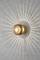 Wall light with golden design casts circular light patterns on grey wall, creating a decorative lighting effect.
