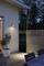A terrace at twilight with an illuminated outdoor area. An olive tree in a pot stands beside a wooden slatted wall.