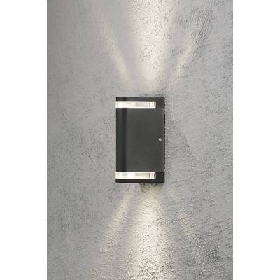 Wall light mounted on a textured grey wall, casting light upwards and downwards. Modern design, illuminating an environment.