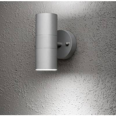 Wall light in a modern design, cylindrical, made of metal, mounted on a textured wall. Light radiates upwards and downwards.