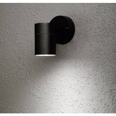 A black, round wall light casts a directional light onto a textured, grey wall.