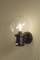 Wall light with a round, clear glass shade revealing a lit bulb. Mounted on a beige-painted wall.