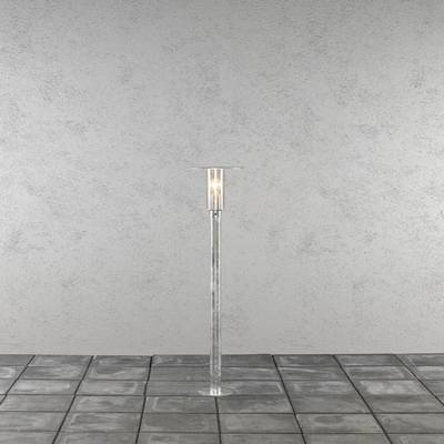 A simple standard lamp with a transparent stand is positioned on a grey tiled floor in front of a grey wall.