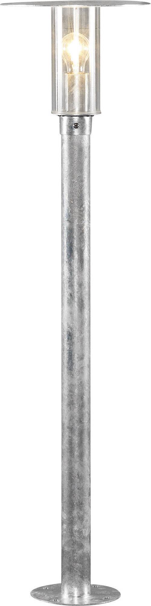 Metal floor lamp with a cylindrical, transparent lampshade. The lamp emits warm light.