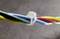 Close-up of a cable with multiple coloured cores, bundled together with a transparent clip. Background out of focus.