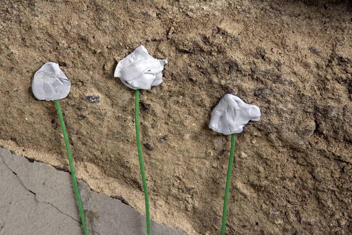 Three green wires attached to a rustic wall, with white putty blobs.