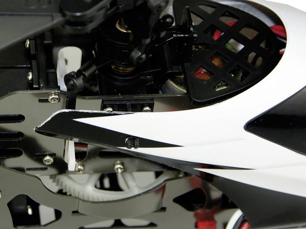 Close-up of a remote-controlled helicopter drive system with visible gears and mechanical components in a black and white casing.
