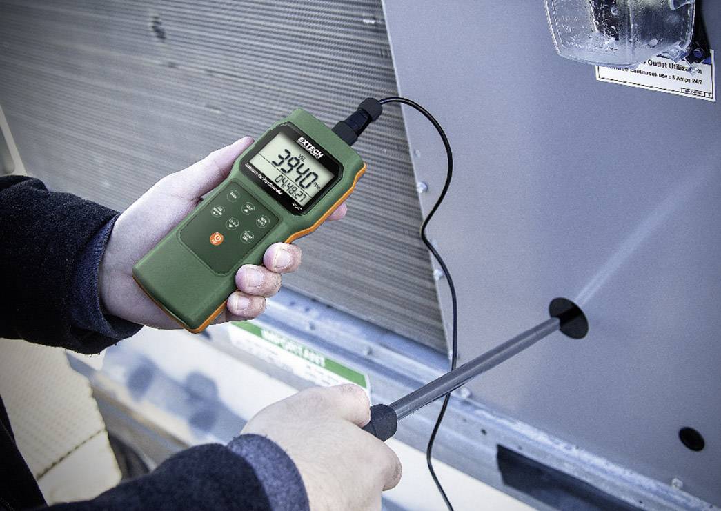 A person is holding a digital thermometer displaying 39.0 degrees Celsius. The thermometer is connected to a metal probe for measurement.