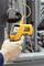 A hand holds an infrared thermometer measuring a temperature of 25.6 degrees Celsius in front of an industrial machine.
