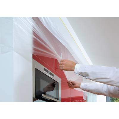 A person is removing the transparent protective film from a red kitchen cupboard above an oven.