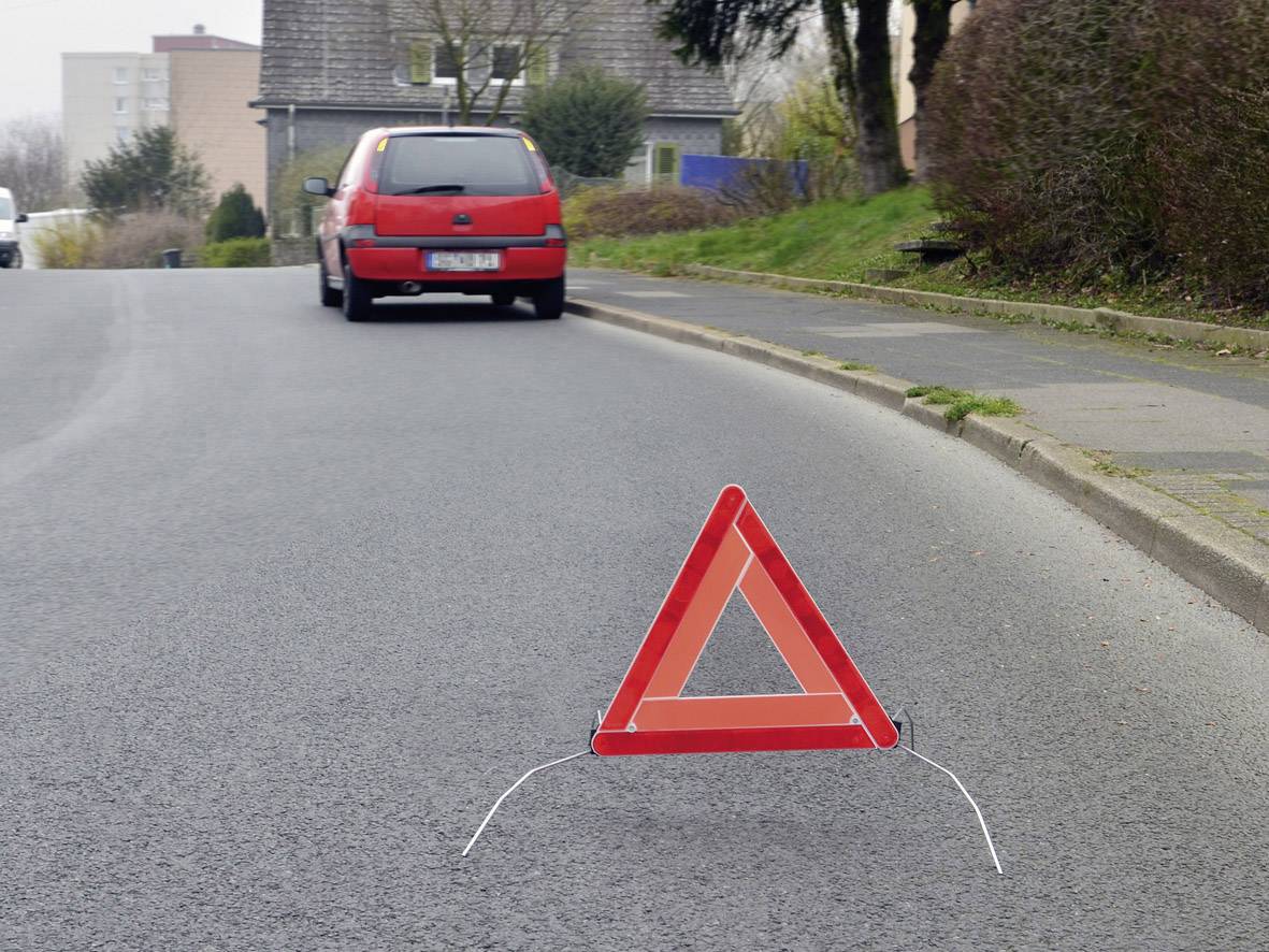 Red car and warning triangle on a road, indicating a potential breakdown or hazard.