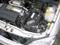Engine compartment of a car with visible battery, radiator, and engine. Various parts are marked with yellow caps.