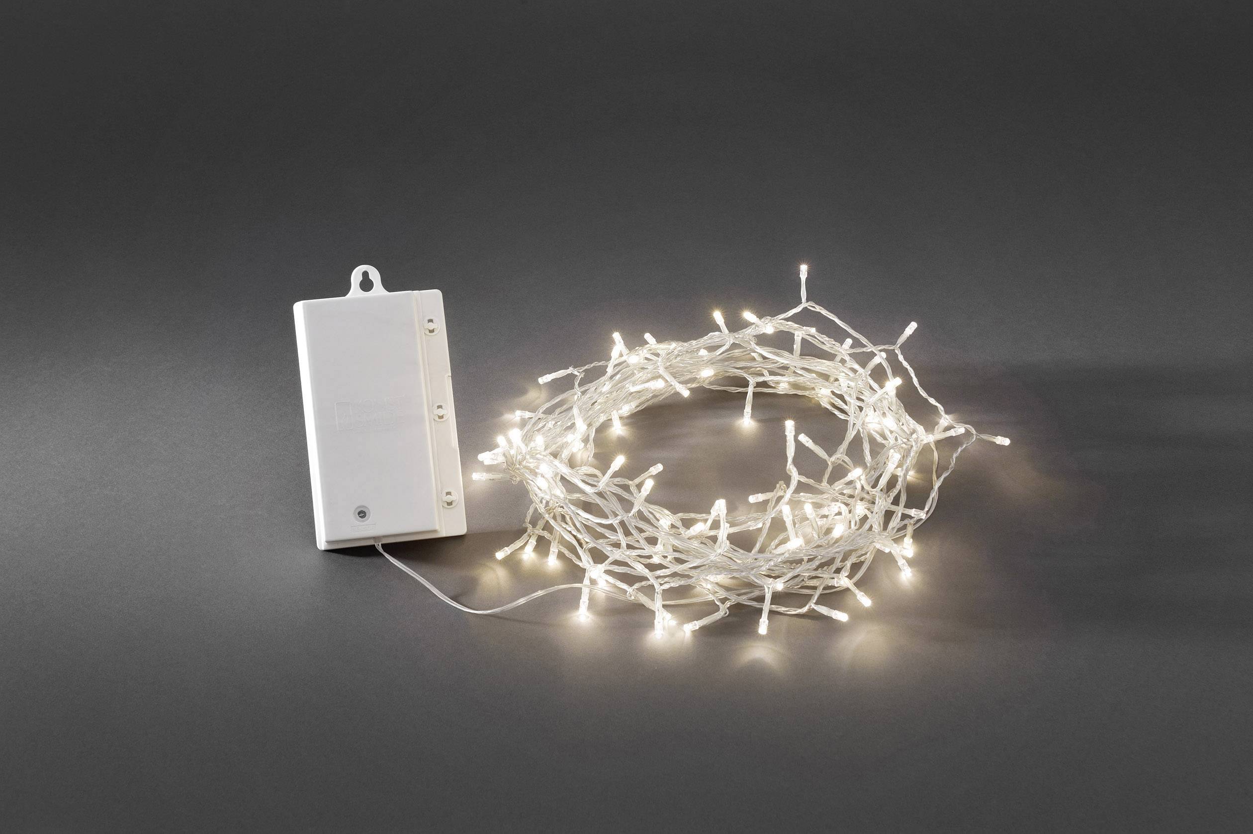 Glowing fairy lights next to a battery box on a grey background.