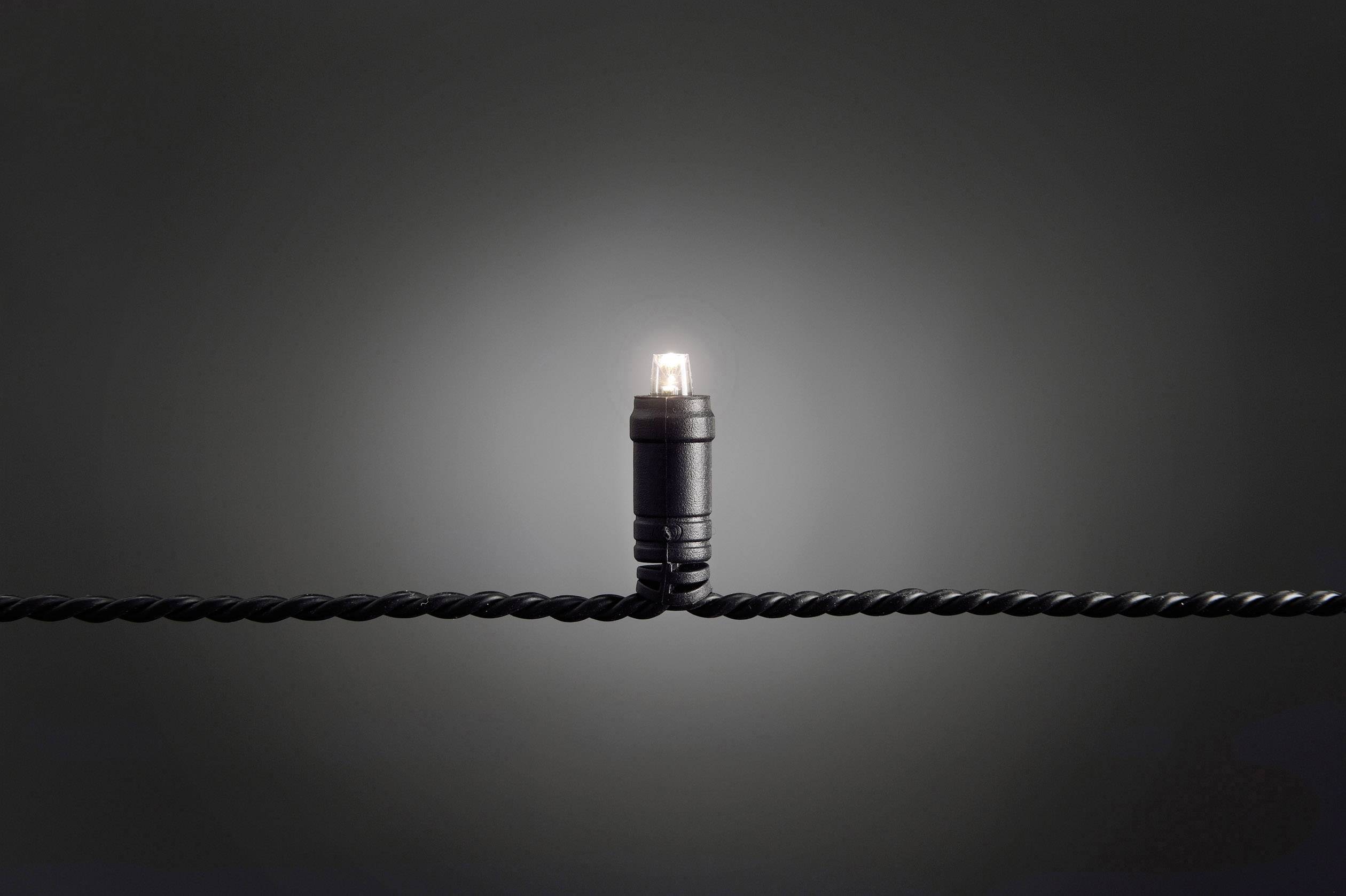 A single light bulb glows on a twisted black cable chain against a dark background.