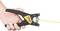A hand is holding a wire stripper that is stripping a yellow cable. The tool has a black housing with a yellow inscription on the handle.