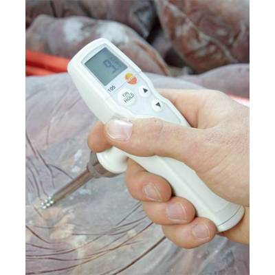 A hand is holding a food-safe digital thermometer inserted into a piece of meat. The display shows the temperature.