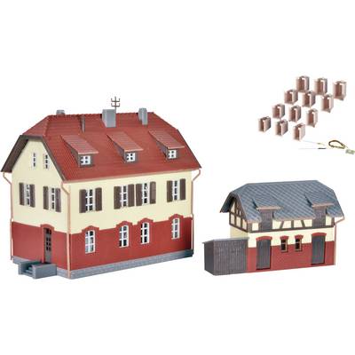 A scale model of a two-storey house with a red roof and outbuilding, surrounded by small brick models.