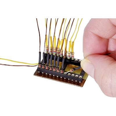 A hand solders wires to a black electronic circuit board with resistors colour-coded in different hues.