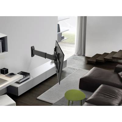 A living room with a flat-screen television mounted on the wall on a swivel arm, next to a sofa and a low coffee table.