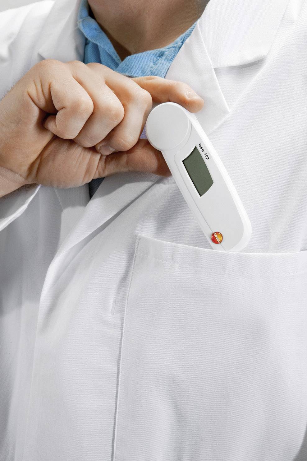 A person in a white lab coat is slipping a digital thermometer into their breast pocket.