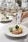 A thermometer is measuring the temperature of a grilled chicken fillet on a plate with vegetables, presumably in a restaurant kitchen.