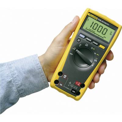 A hand is holding a digital multimeter with a yellow casing. The display shows '1000 V AC'.