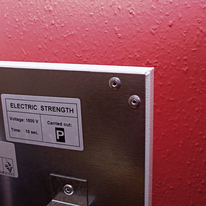 Metal sign on a red wall shows 'Electric Strength', voltage 1500 V, duration 10 sec., with letter 'P'.