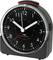 Black alarm clock with white hands and numbers on the dial, showing 6:15.