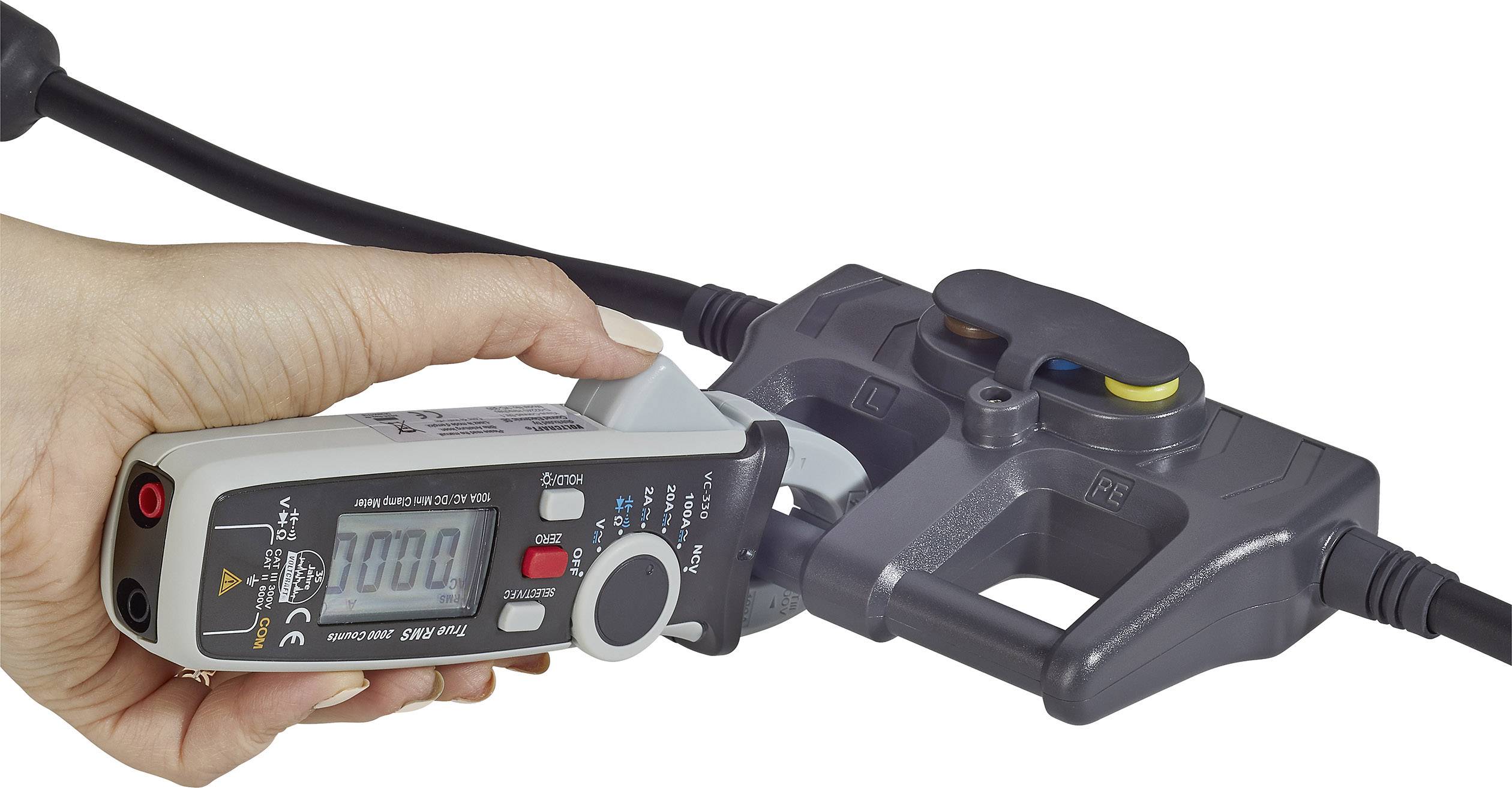 A hand is holding a digital measuring device connected to an electrical adapter, displaying a reading of 0.00 on the screen.