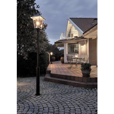 Illuminated terrace of a house at dusk; street lamp posts light up the seating area with a table and chairs.