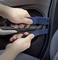 Hands are using blue lever tools to remove the car door panel.