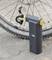 Electric bicycle pump stands next to a bicycle tyre on tarmac. Pump display shows pressure. Tyre has a coarse tread pattern.