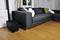 Dark grey sofa in a modernly furnished living room with wooden flooring. A black device sits to the left of the sofa.