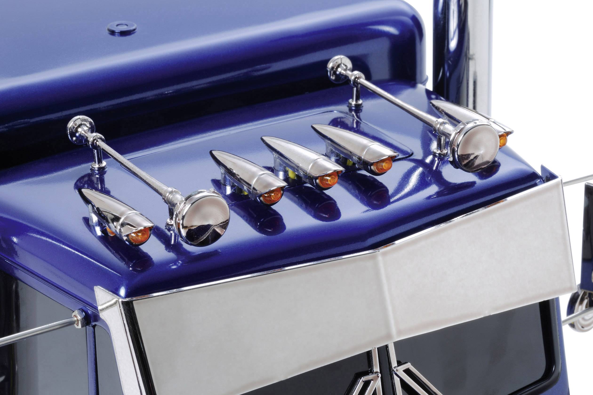Blue lorry with gleaming chrome details on the roof, including four round headlamps and six amber-coloured position lights.