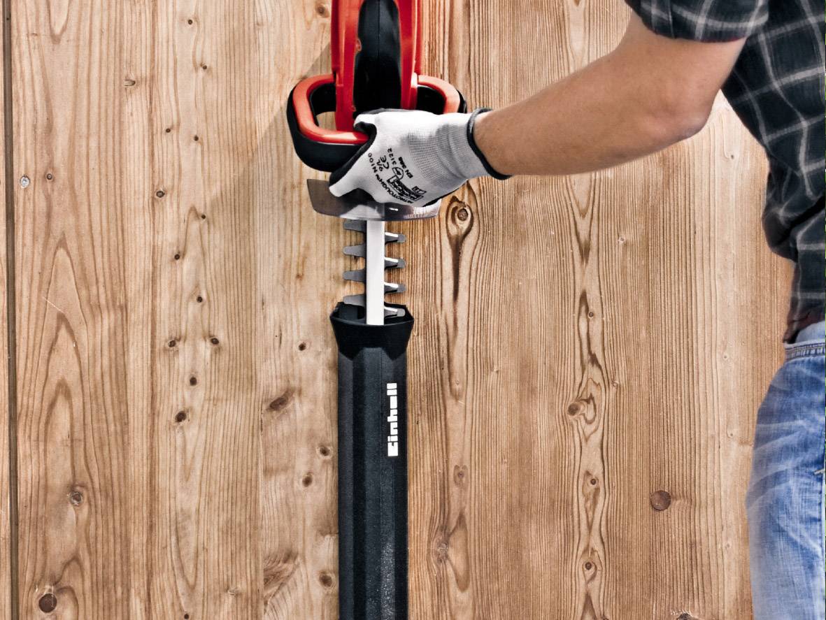 A person is operating a red reciprocating saw mounted on a wooden surface.