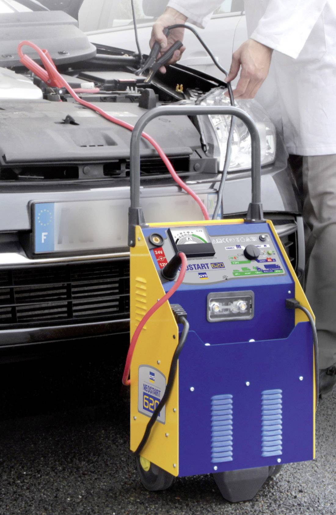 A person is jump-starting a car with a portable jump starter. Jump leads are connected to the car battery.