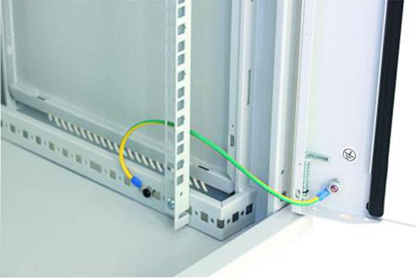 A green and yellow earthing cable connects two metal surfaces in an electrical cabinet to ensure safe electrical grounding.