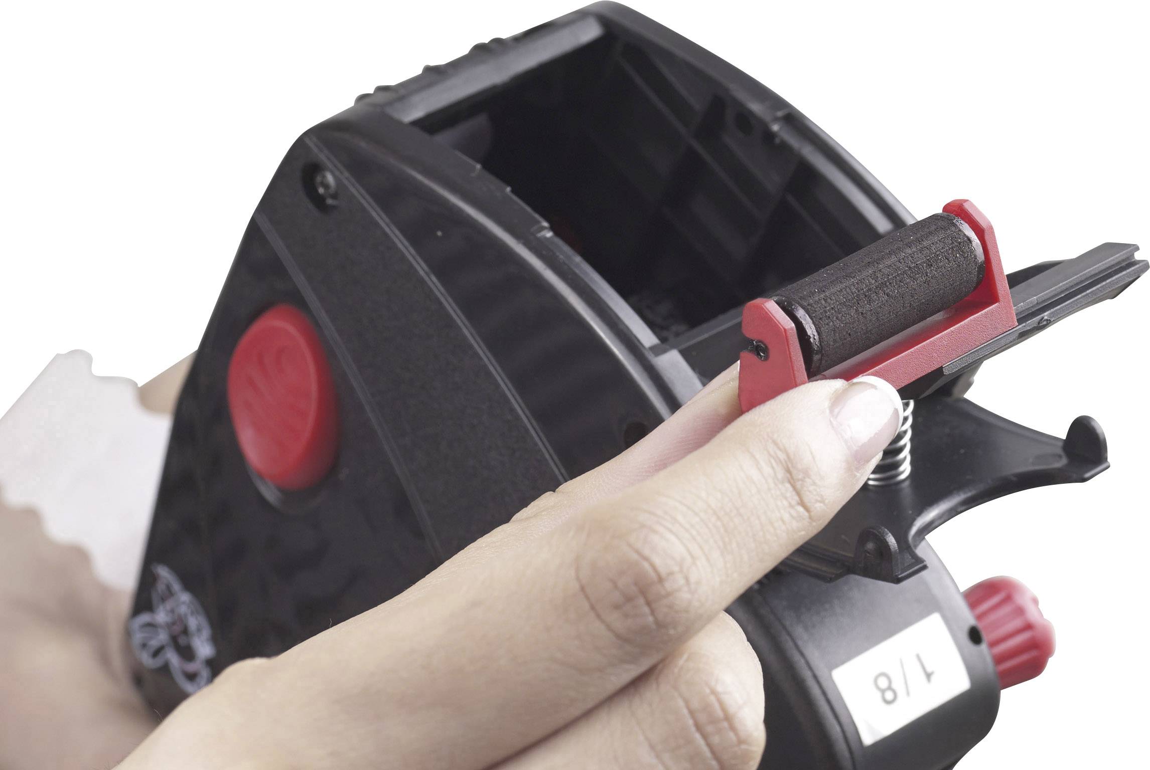 A person is holding a black label printer used for printing price labels. A white label is being inserted.